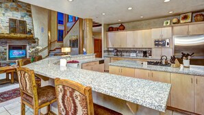 Una cocina amplia con encimeras de granito, armarios de madera y chimenea de piedra.