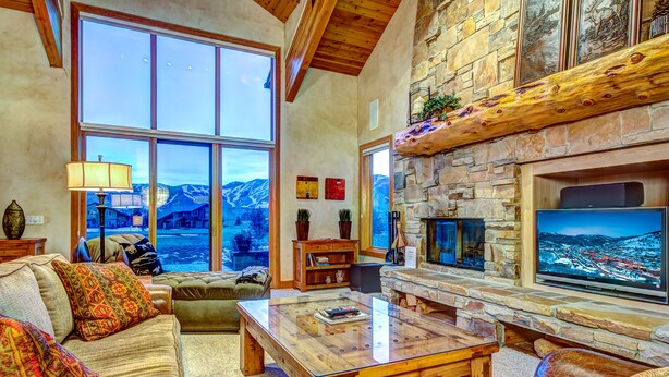 Una sala de estar acogedora con chimenea de piedra, ventanas amplias y un televisor de pantalla plana.