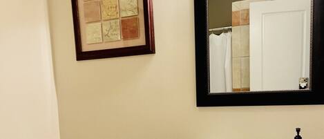 A bathroom with a toilet, sink, and framed artwork on the wall.