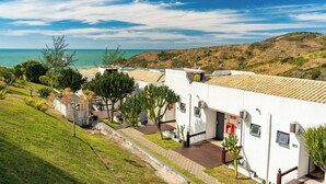 Un bâtiment situé sur la côte, doté d’un toit plat, d’une entrée pavée et offrant une vue sur la mer.