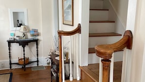 Eine Holzt Treppe mit weißen Spindeln, ein Schreibtisch mit Lampe und ein gerahmtes Bild an der Wand.