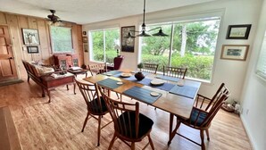 Un espace repas comprenant une grande table en bois, plusieurs chaises et un ventilateur de plafond.