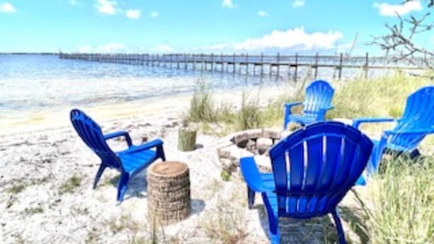 Une scène de plage avec des chaises bleues et un poteau en bois.