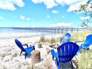 A beach scene with blue chairs and a wooden post. - Bay Front Home W/Private Bch in Historic Neighborhood. Family/Dog Friendly (Panama City)
