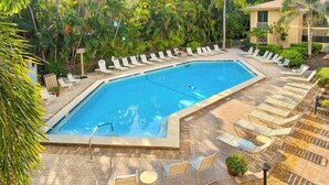 Ein rechteckiger Pool mit Fliesen umgeben, mit Liegestühlen und Blumentöpfen.