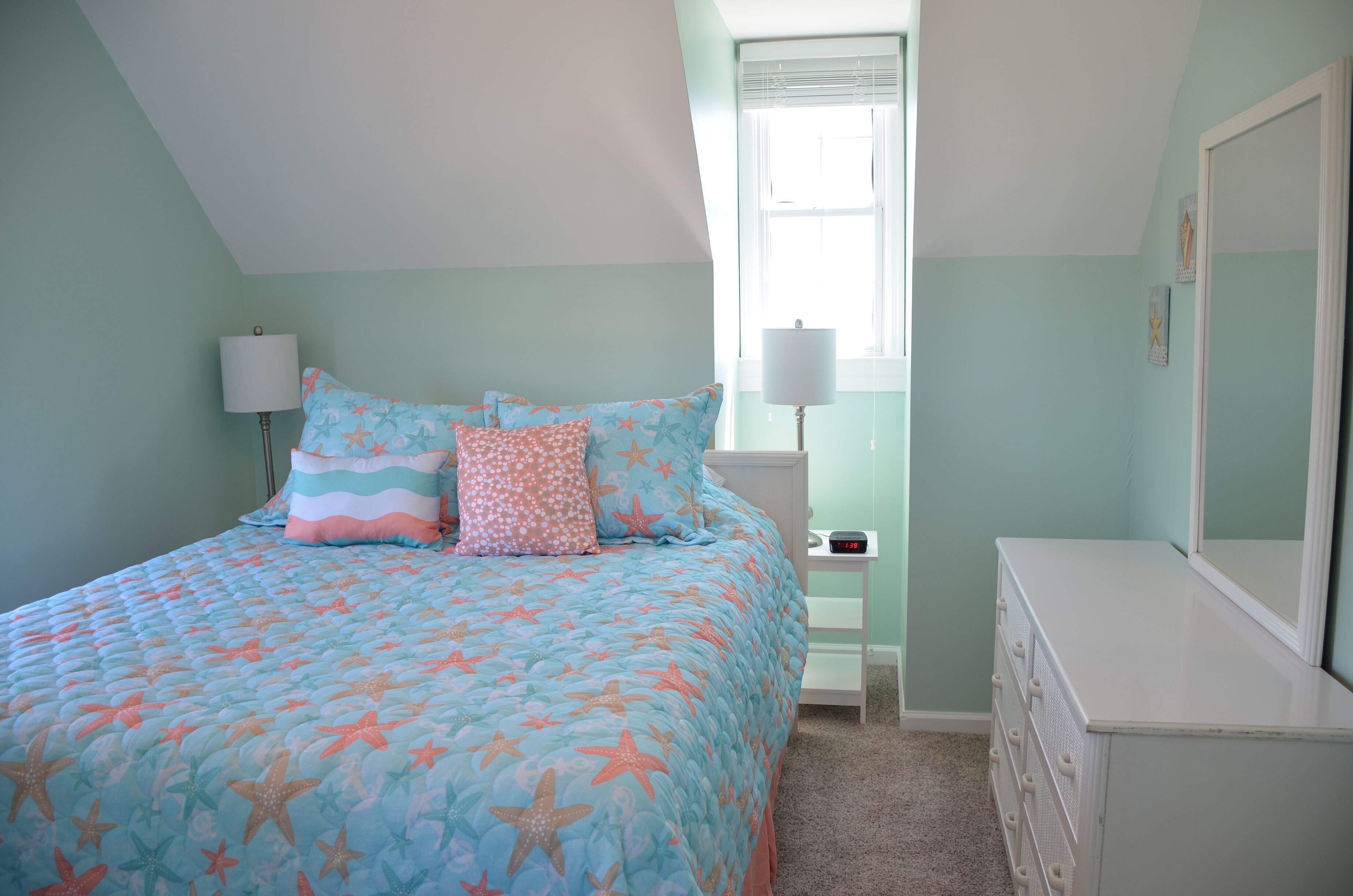 Une chambre à coucher avec un lit, une commode, une table de chevet et une fenêtre.