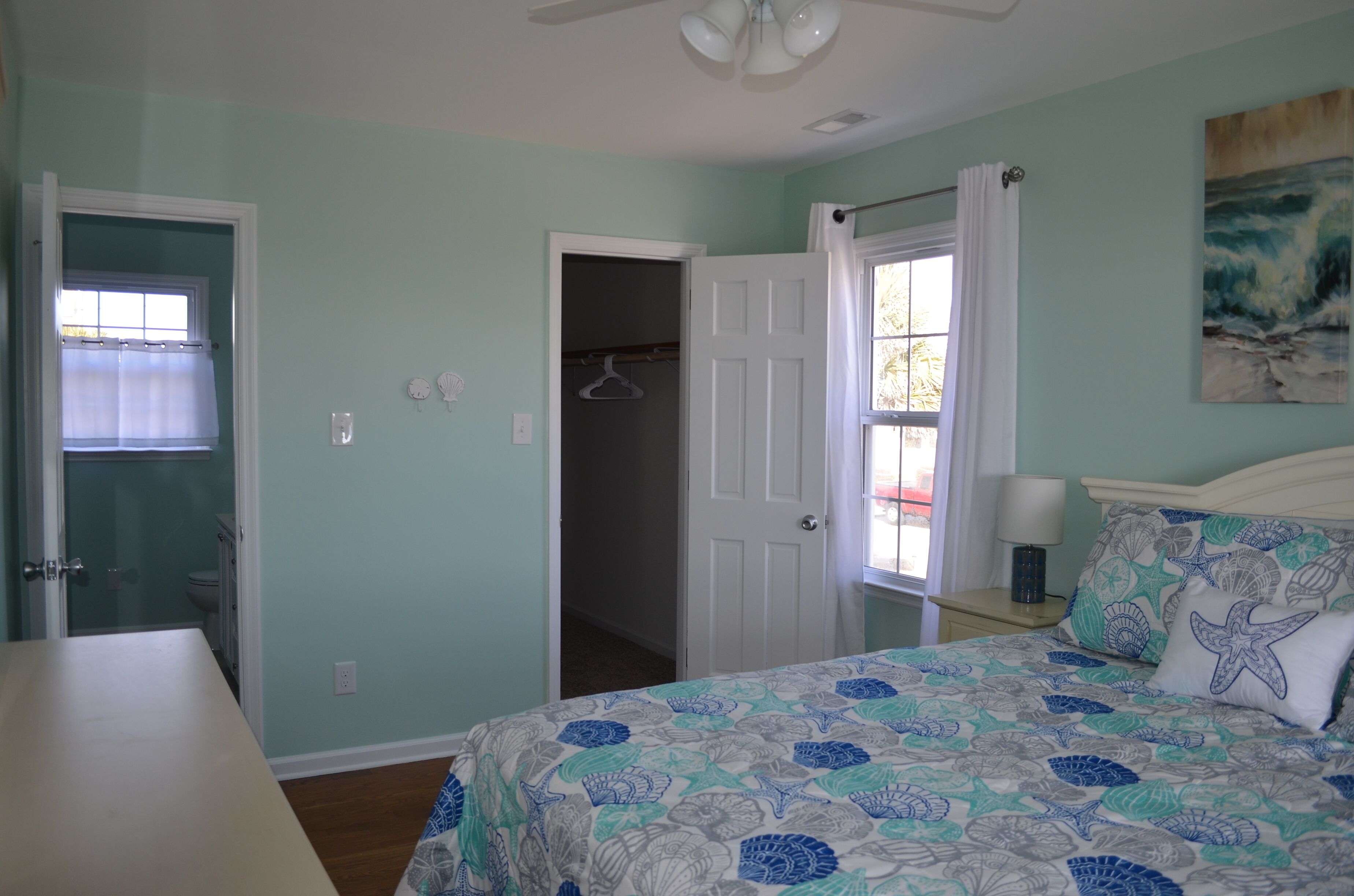 A bedroom with a bed, a closet, a bathroom, and a window with curtains.