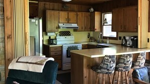 A cozy kitchen with wooden cabinets, a central island with bar stools, and a refrigerator.