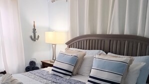 Una cama bien hecha con toallas enrolladas, una colcha estampada y almohadas a juego.