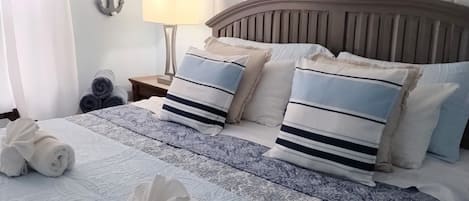 A neatly made bed with rolled towels, a patterned bedspread, and matching pillows.