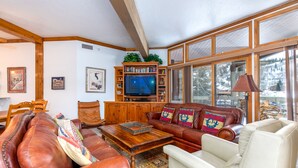 Ein gemütliches Wohnzimmer mit Ledersofas, einem Holztisch und einem Fernseher.