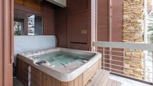 Ein Whirlpool in einer Holzhütte mit einer Steinwand und einem Balkon.
