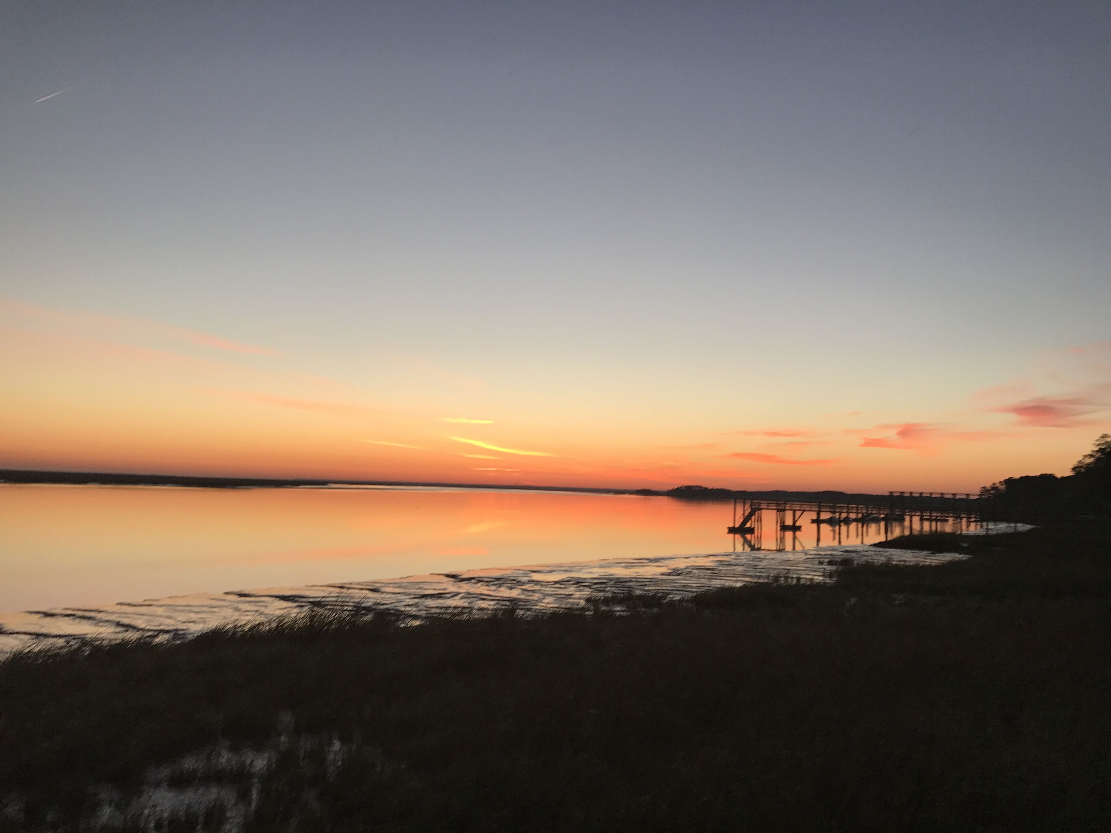 Un tramonto sul lago calmo, con un pontile che si protende verso l'acqua.