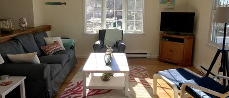 A living room with a sofa, a coffee table, a TV, and a chair.