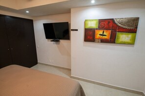 A bedroom with a bed, a television, and a wall-mounted artwork.