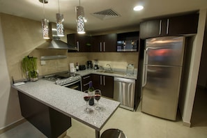 A modern kitchen with a central island, stainless steel appliances, and pendant lighting.