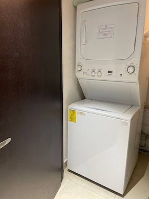 A compact washer and dryer unit with control knobs and a label on the top.
