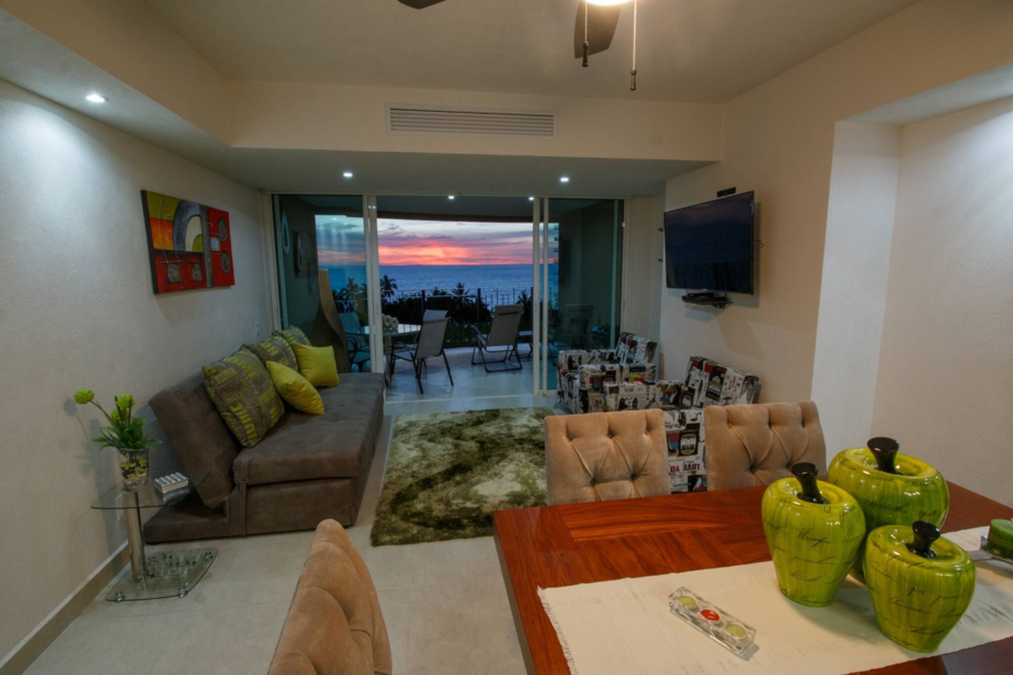 A modern living room with a sofa, armchairs, a coffee table, and a TV.