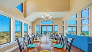 A dining room with a long table, chairs, and a chandelier. - Premier Oceanfront Dog Friendly with Pool, Hot Tub, Elevator, Theater, Tiki Bar (Salvo)