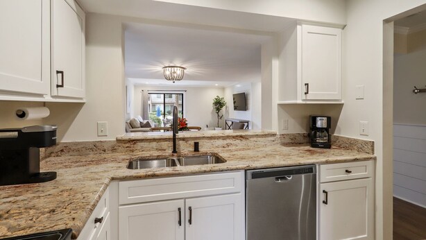 A modern kitchen with white cabinetry, granite countertops, stainless steel appliances, and a central island with a sink. - Courtside 61- Updated Flat - Pool View - Free Tennis (Hilton Head Island)