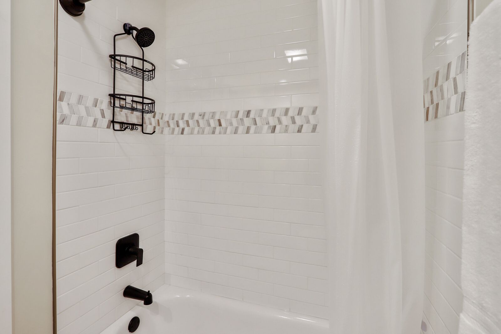 A modern bathroom with white subway tiles, a shower area, and a bathtub.