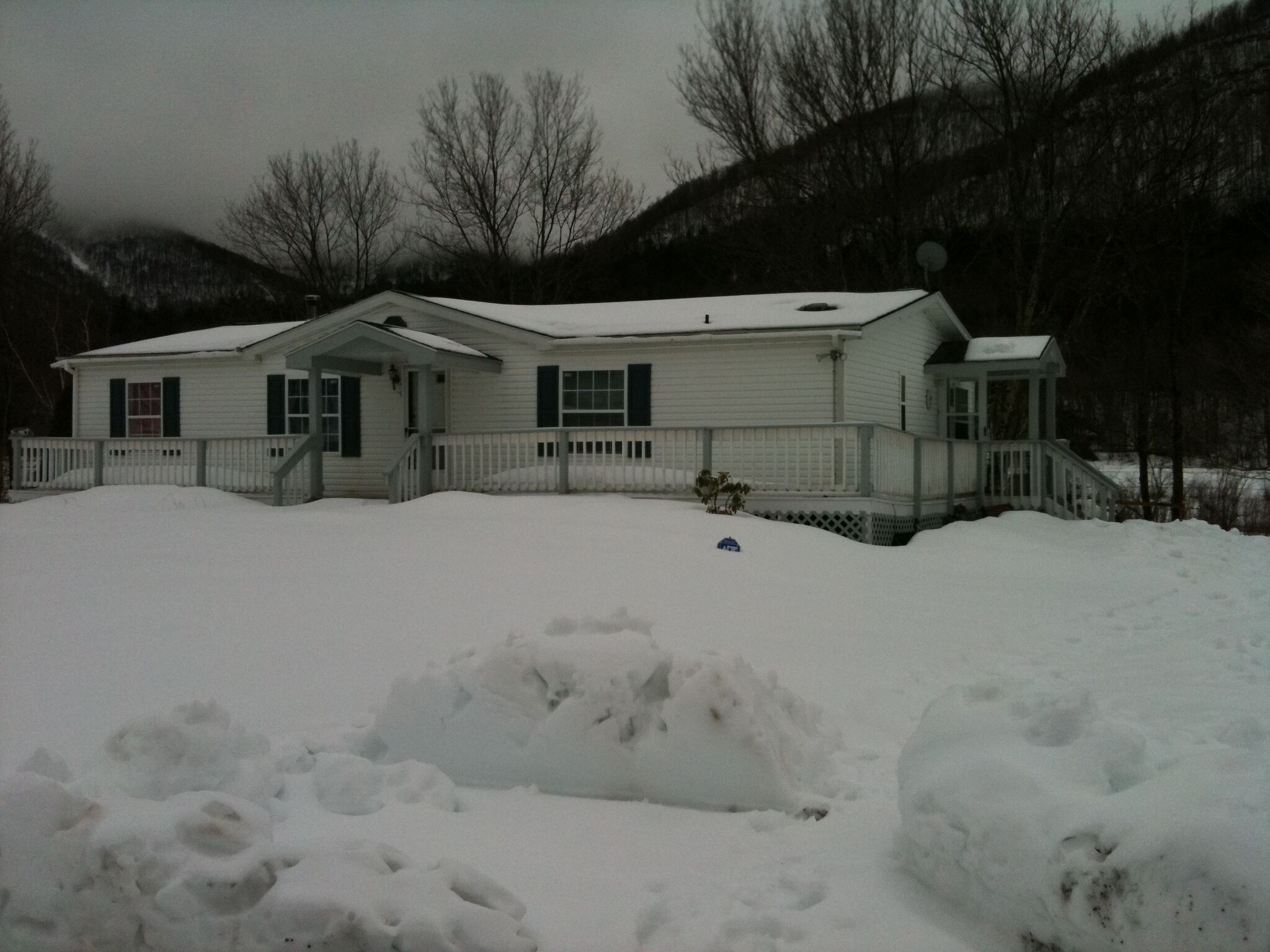 A two-story house with a snow-covered front yard and a small porch.