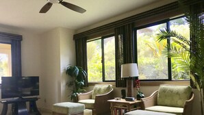 A living room with a television, two armchairs, a coffee table, and a large window with curtains. - Spacious remodeled town home, beach access,quiet prime location in Princeville (princeville)