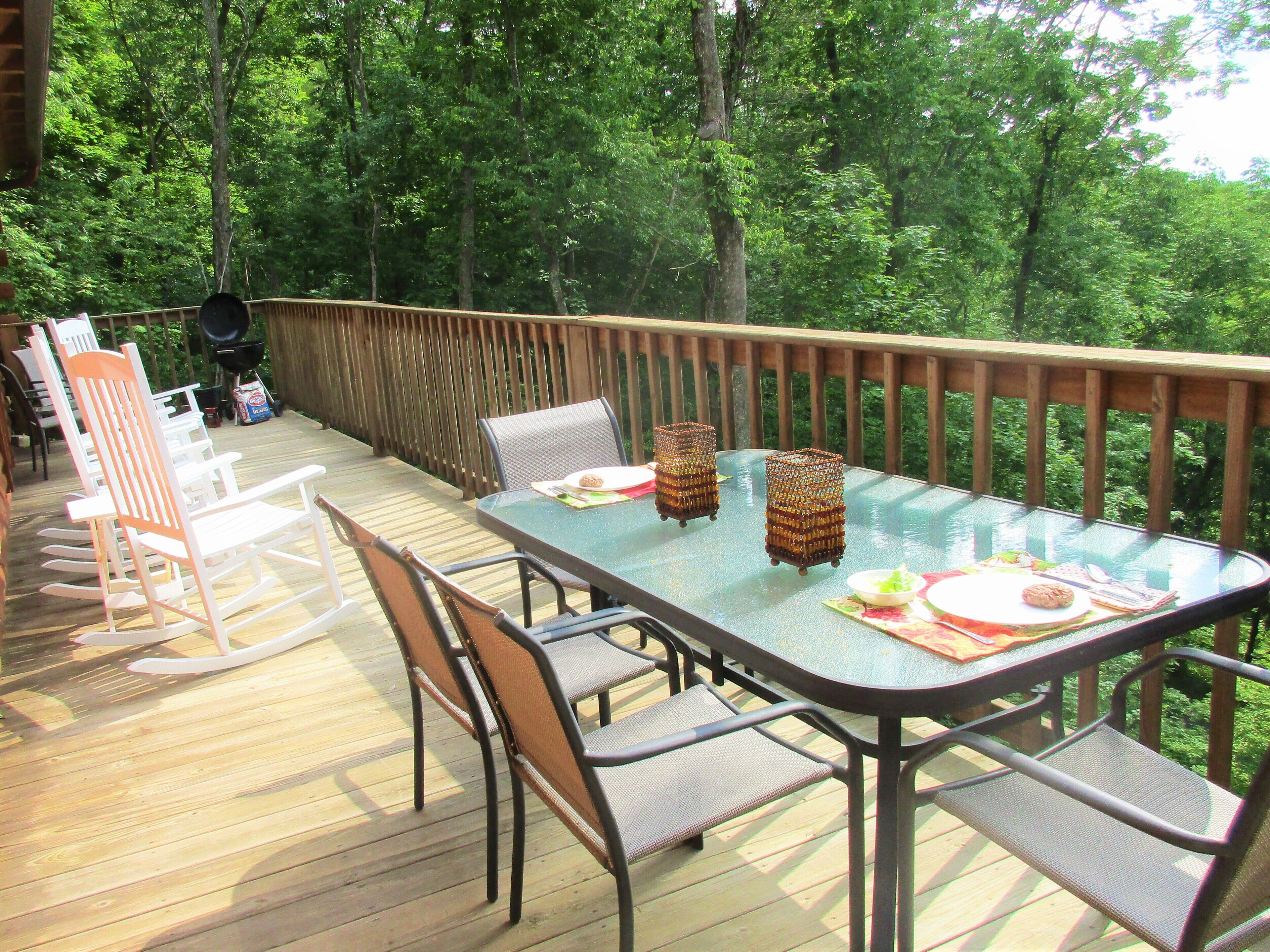 Een terras met een tafel met glazen blad, omringd door stoelen, en een houten balustrade.