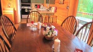 A wooden dining table set with a candle, a glass of red wine, and a fruit bowl. - ALPINE LOG CABIN/COZY, COMFORTABLE, MODERN/BLUE RIDGE MOUNTAINS NEAR BOONE N.C. (Boone)