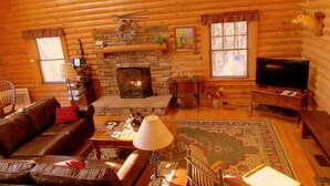 A cozy log cabin interior with a stone fireplace, leather sofa, and a television. - ALPINE LOG CABIN/COZY, COMFORTABLE, MODERN/BLUE RIDGE MOUNTAINS NEAR BOONE N.C. (Boone)