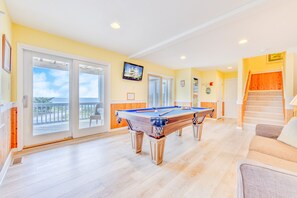 Una mesa de billar en una habitación luminosa con vistas al exterior.