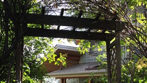 A pathway leading to a house with a wooden pergola and a fenced garden area. - Beautiful home in private setting yet only15 min to town  & 10 min to lake (Durango)