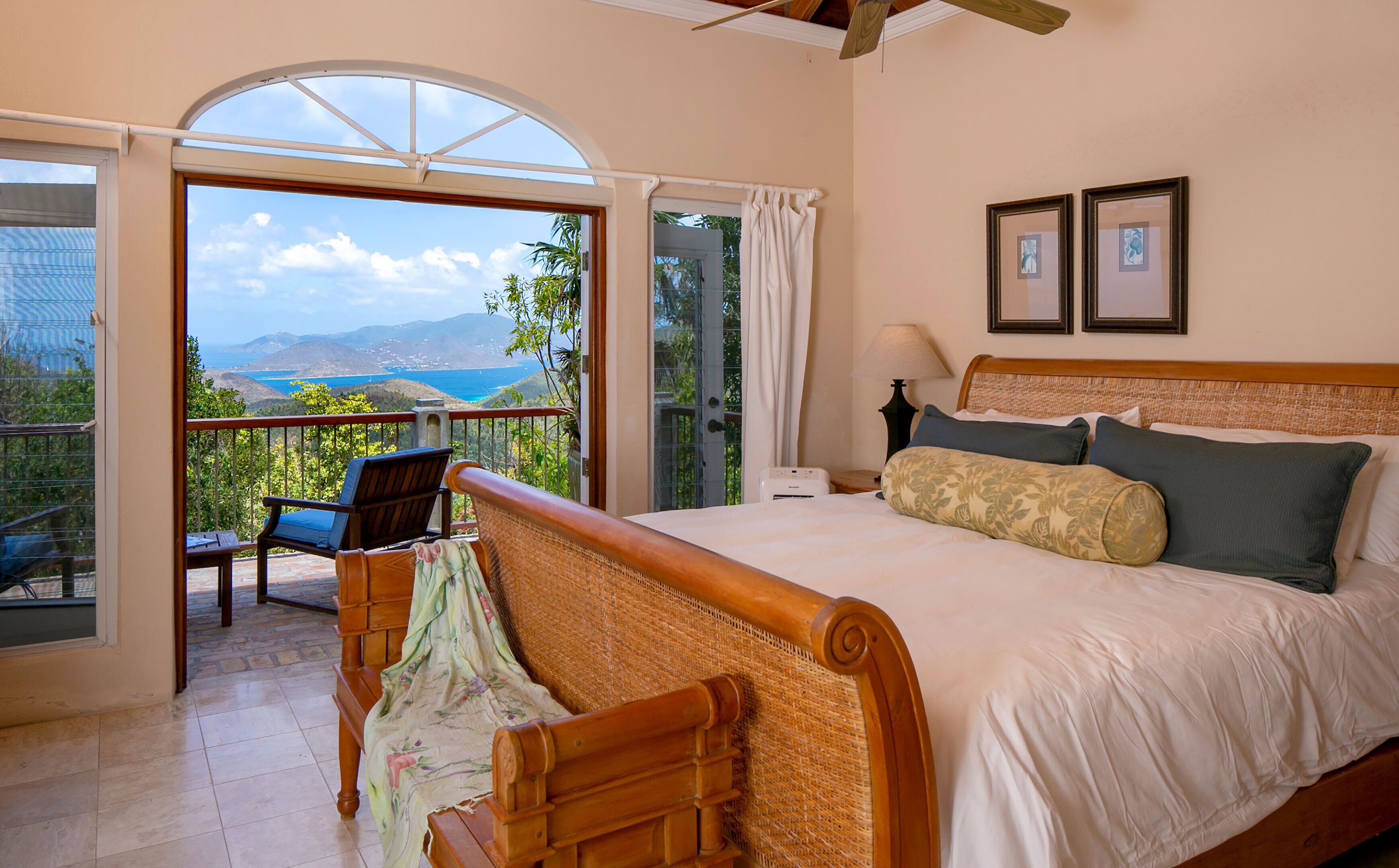 Une chambre avec un grand lit, un balcon donnant sur la mer et un fauteuil.