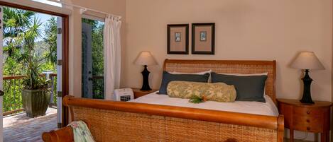 A room with a bed, two bedside lamps, a potted plant, and a view of the outdoors.