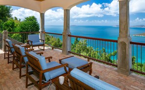 A covered outdoor seating area with wooden furniture and a view of the sea. - Mango Bay: Amazing North Shore Views! (St. John)