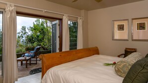 Une chambre avec un lit, une chaise, une table et une vue sur la verdure.