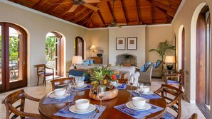 Un coin repas avec une table ronde dressée pour quatre personnes, entourée de chaises en bois.