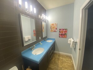 A bathroom with two sinks, a large mirror, and two wall-mounted lights.