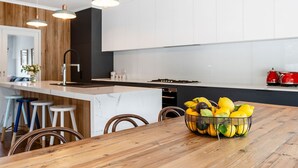A modern kitchen with a wooden island, bar stools, and a fruit bowl. - SALTWATER POOLSIDE -8m Heated* Pool, an entertainers delight -BONUS*NIGHTS 2026 (rye)