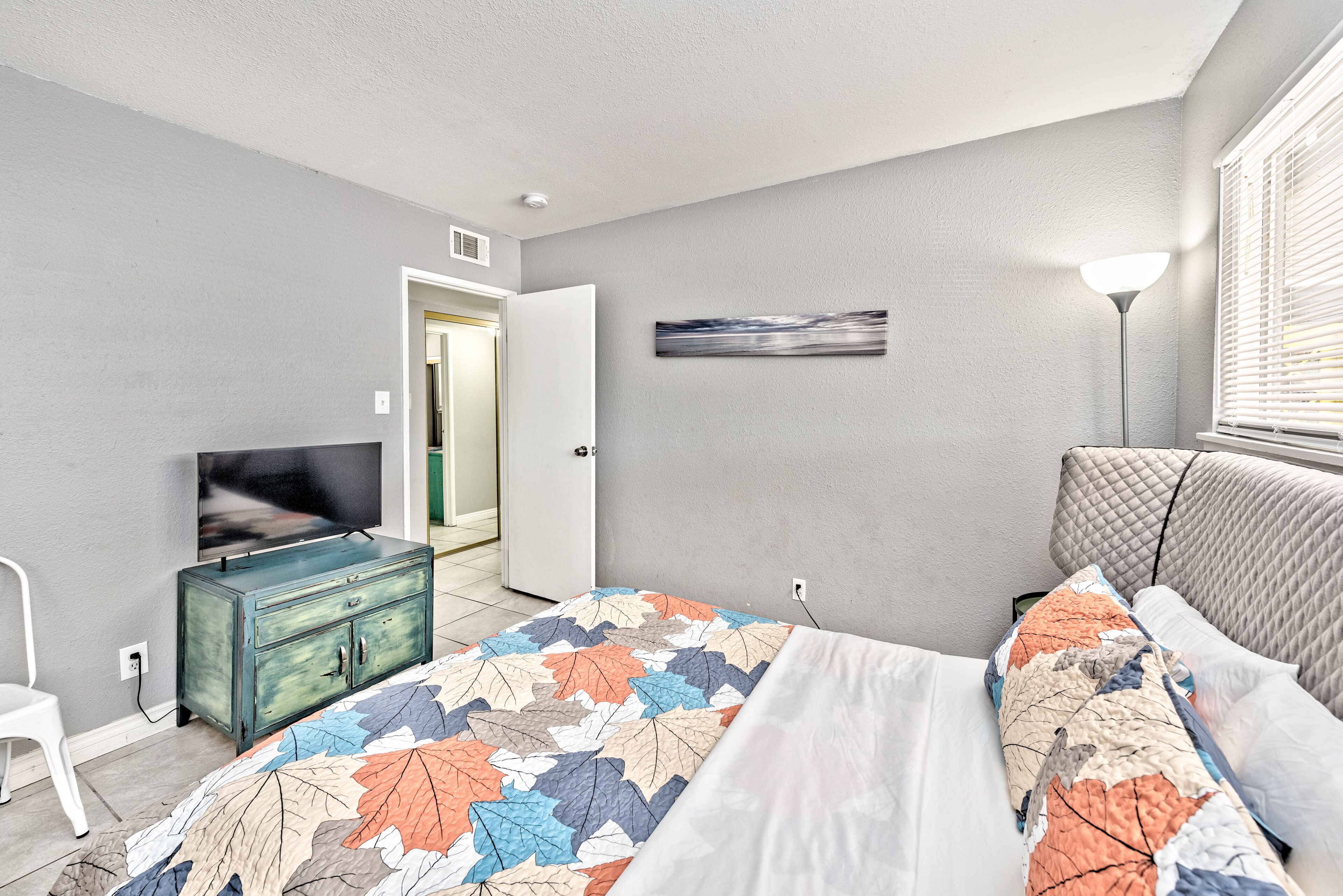 Un dormitorio con cama, cómoda, televisor y un cuadro en la pared.