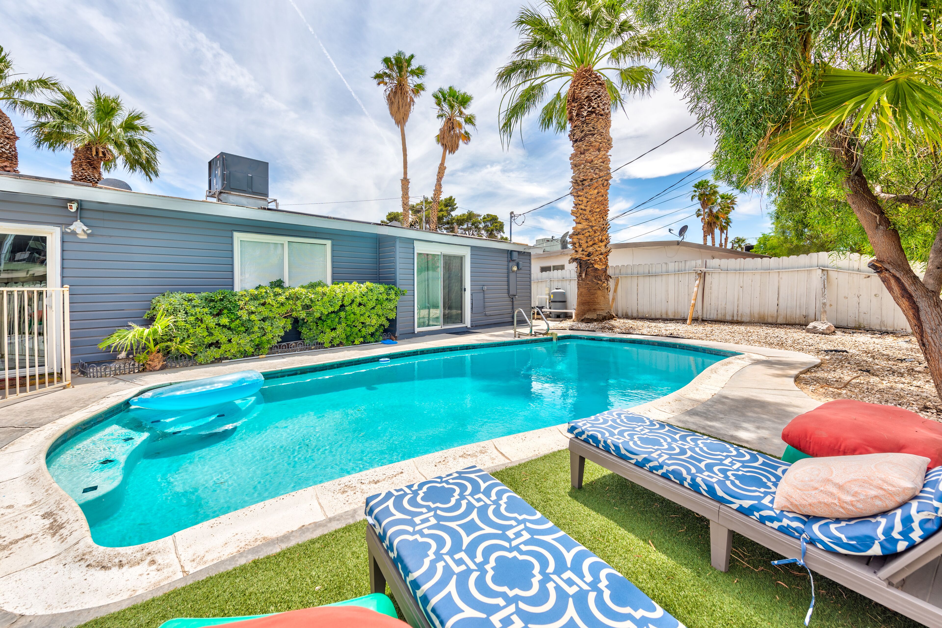 A swimming pool with lounge chairs and palm trees.