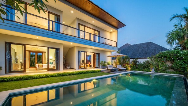 Une maison moderne à deux étages, dotée d’une piscine, de grandes portes vitrées et d’un jardin bien entretenu.