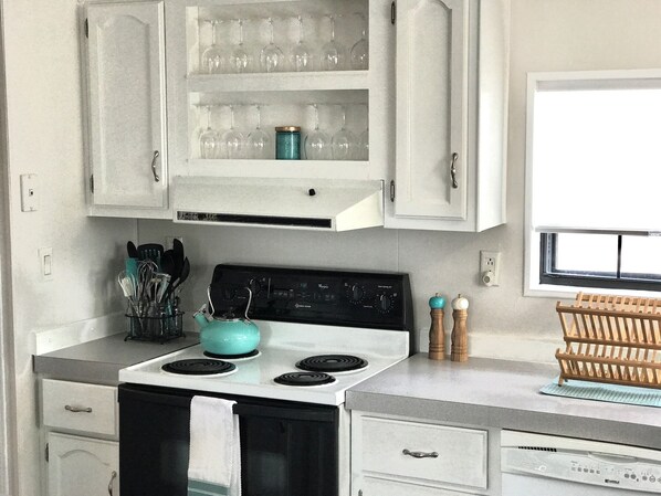 A kitchen with white cabinets, a stove, and a window.