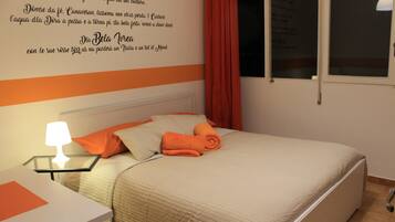 A bedroom with a bed, pillows, a nightstand, a lamp, and a window with curtains.