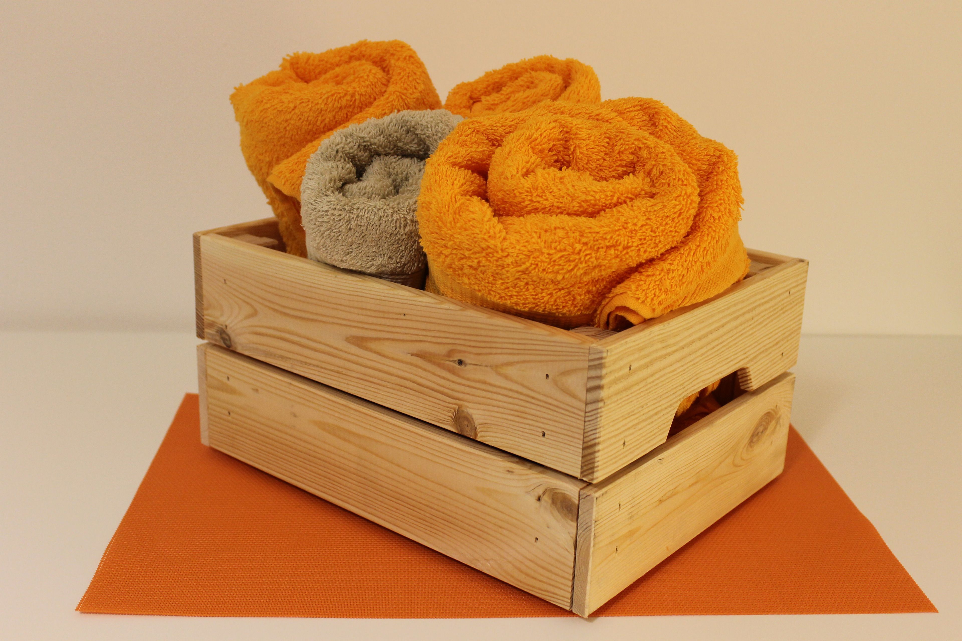 A wooden crate with rolled towels in orange and gray colors.