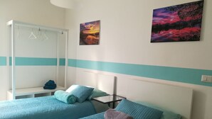 Une chambre avec deux lits, une armoire et deux tableaux accrochés au mur.