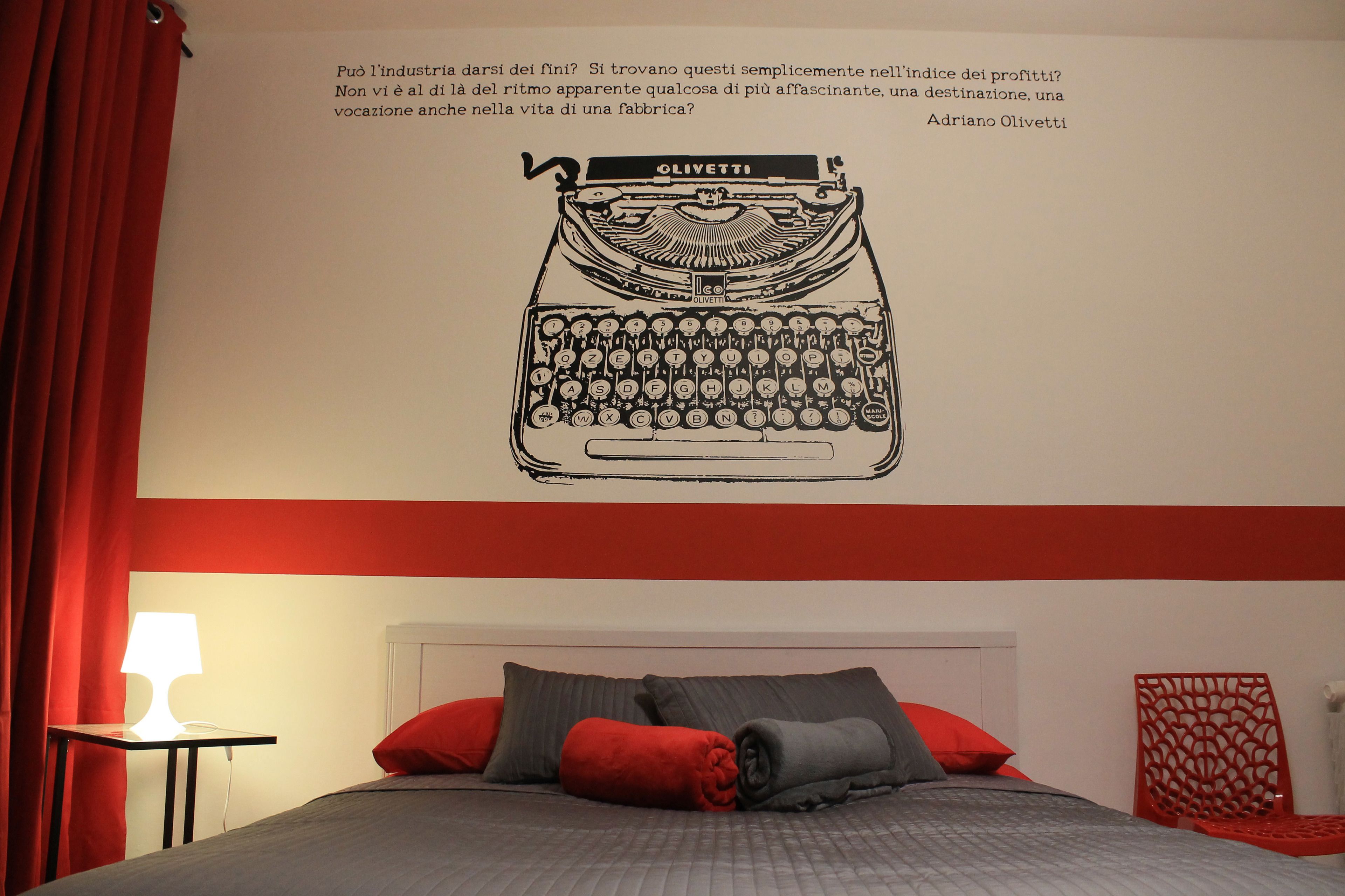 A bedroom with a bed, pillows, a nightstand, and a wall-mounted lamp.