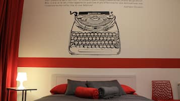 A bedroom with a bed, pillows, a nightstand, and a wall-mounted lamp.
