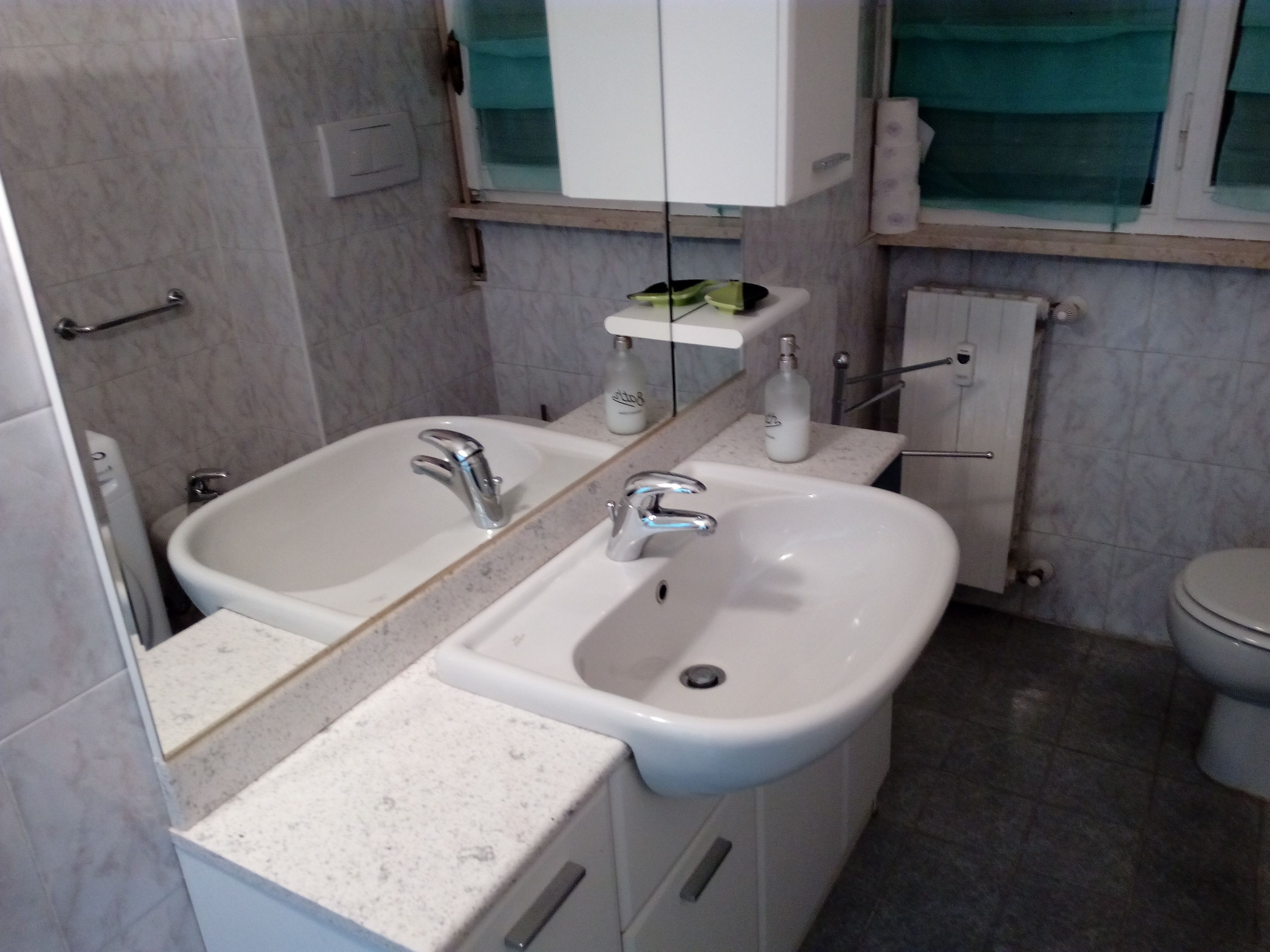Un baño con dos lavamanos, un espejo y un inodoro.