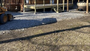 Een houten blokhut met een groen dak, een veranda en een overdekt terras.